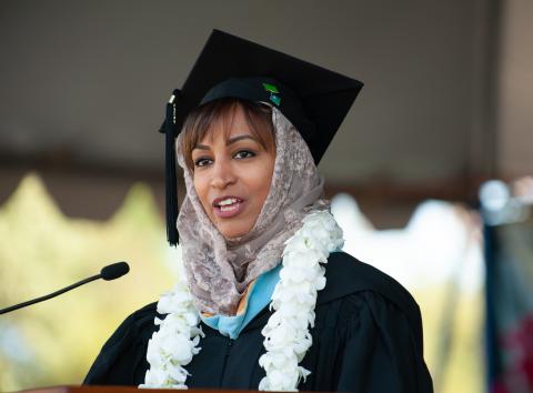 A woman in graduation robes speaking at commencement