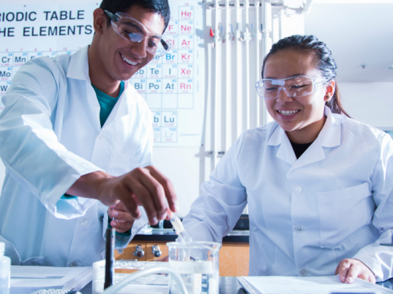 student putting liquid into a beaker